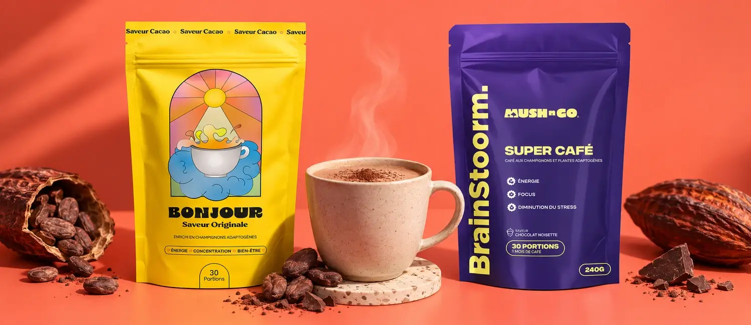 La busta gialla di Bonjour Drink e la busta viola di Brainstoorm di Mush N Go ai lati di una tazza fumante di cioccolata, tra baccelli e fave di cacao, su sfondo corallo