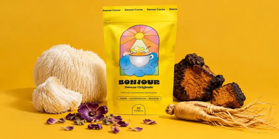 Busta di Bonjour Drink tra criniera di leone, pezzi di chaga, fiori di malva e radice di ginseng su sfondo senape