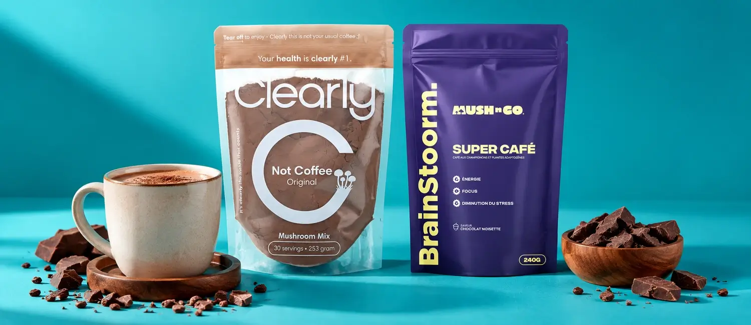 La busta trasparente di Clearly Not Coffee accanto alla busta viola di Brainstoorm di Mush N Go, con una tazza di bevanda al cacao, su sfondo turchese