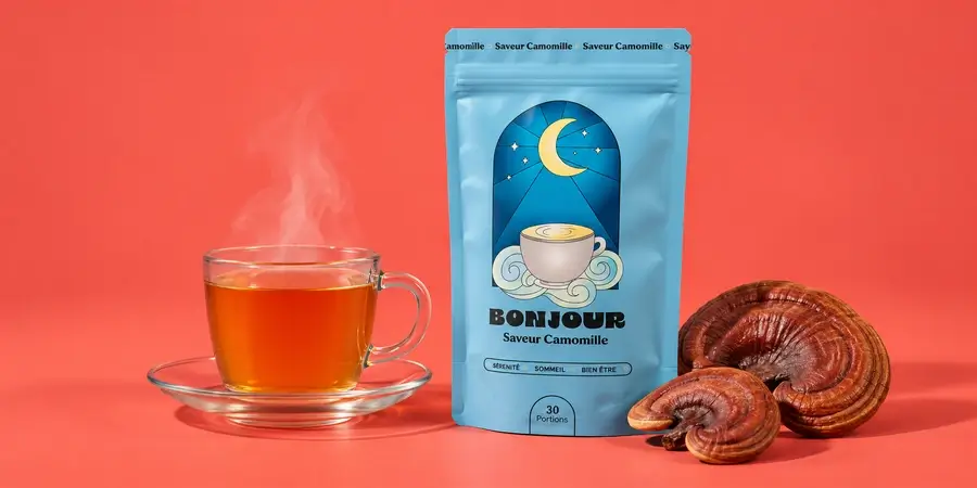 Busta di Bonjour Drink al gusto Camomilla con una tazza fumante e reishi essiccato su sfondo corallo