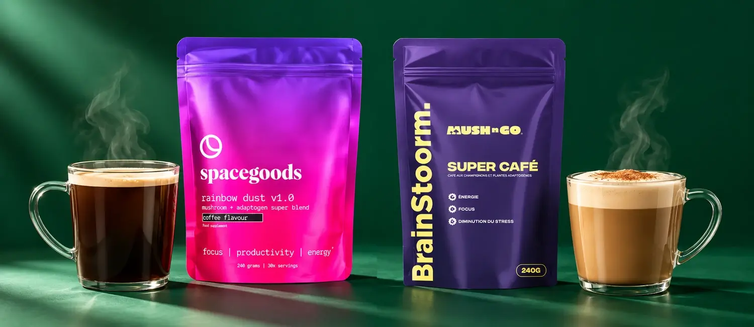La busta di Rainbow Dust di Spacegoods e la busta viola di Brainstoorm di Mush N Go tra due tazze di vetro fumanti, un caffè nero e un latte schiumato, su sfondo verde abete